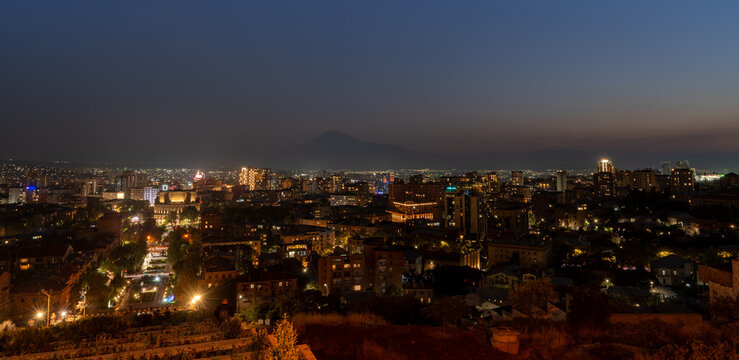 Night cityscape photograph of illuminated Yerevan city skyline from Yerevan Cascade with Mount Ararat in background Armenia.