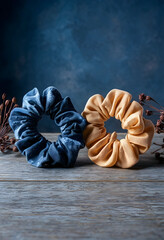 Obraz premium Hair accessories and fashion trends, blue and beige fabric scrunchies on rustic wooden table with dried flowers for beauty and lifestyle photography
