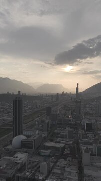 Aerial view over downtown Monterrey  with views of the skyline during golden hour at sunset with mountains and dramatic backlight, Nuevo Le&oacute;n. Vertical video. D-Log M