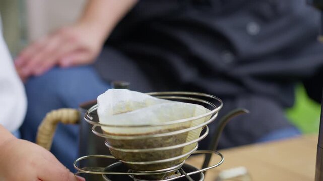 Close-up of coffee brewing in a metal pour-over dripper with a paper filter, showcasing the artisan process of preparing a specialty craft beverage.