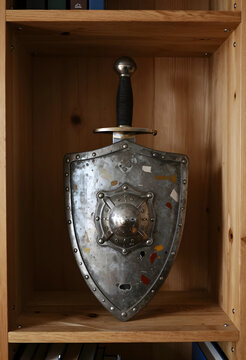 Security and protection concept, medieval shield and sword displayed on a wooden shelf as historical armor for defense and heritage preservation