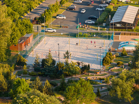 Aerial view of modern urban playground with beach volleyball, and kids recreational zone. Landscape design that includes trees and various other green areas.