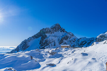 Fototapeta premium Snow-capped peak towering above a remote mountain cabin, Yulong Snow Mountain, Lijiang