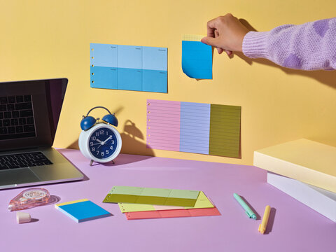 Workspace with laptop, alarm clock, and colorful sticky notes