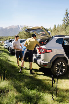 UGC Friends packing hiking gear from car in mountain parking lot