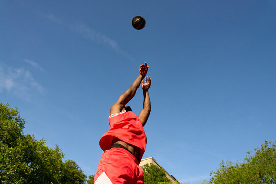 Basketball Player Shoots Ball Towards the Hoop on a Sunny Day