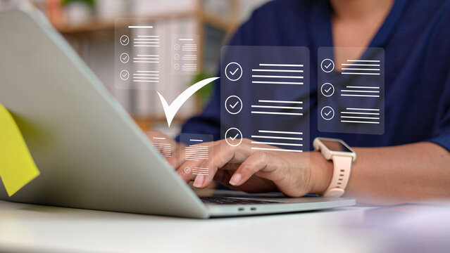 Businesswoman typing on laptop with digital online survey checklist document and check mark icons. Female employee completing evaluation task or quality management form at desk.