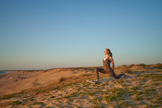 Fit Woman Practicing Yoga Stretch On Sandy Beach At Sunset With Ocean