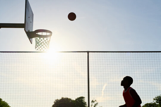 Man Shooting Basketball During Sunset at Outdoor Court