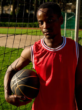 Basketball Player Holds Ball at Court During Daylight