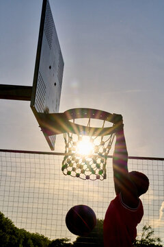 Player Dunks Basketball at Sunset During Outdoor Game