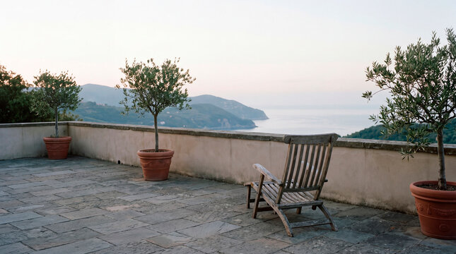 Empty wooden chair overlooks calm sea from terrace at quiet dusk retreat