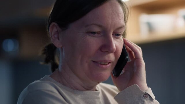 Concerned middle-aged woman on phone at home, serious expression and thoughtful mood, 4K