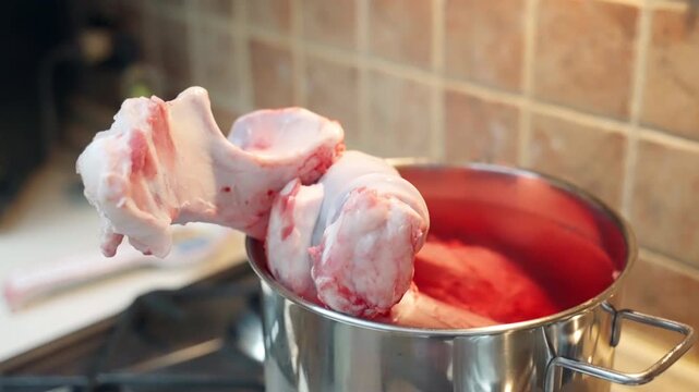 Raw beef bone for domestic pet feeding, meat wastes as a natural food for pets, bone with blood and cartilages in cooking pan prepared for boiling