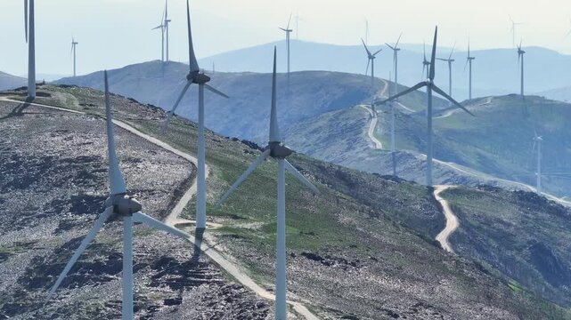 Wind turbines generating clean, renewable energy on a vast mountain wind farm. The spinning blades convert wind into sustainable electricity