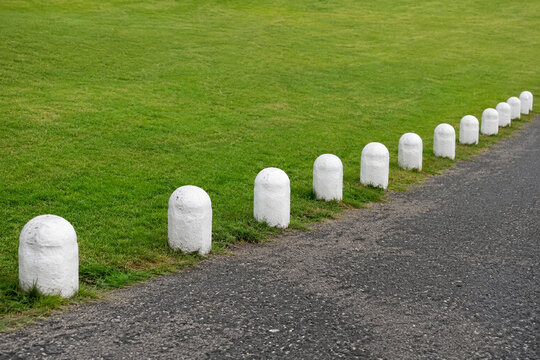 Row of white stone bollards and manicured lawn, boundary and landscaping concept