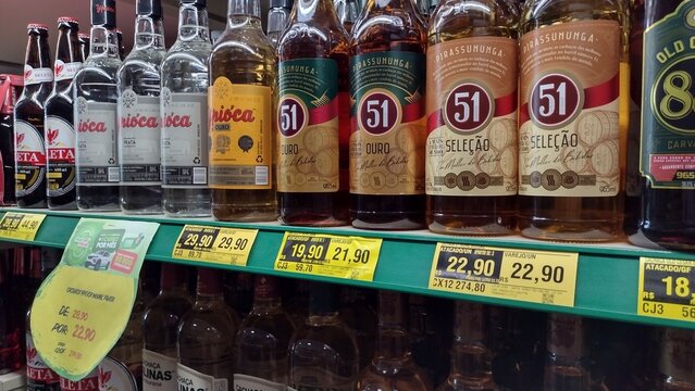 ITABIRA, BRAZIL - AUGUST 26, 2026: Row of Brazilian cachaca bottles including brands Pirassununga 51, Ypioca, and Old Cesar 88 with price tags on supermarket shelf in Itabira, Minas Gerais.