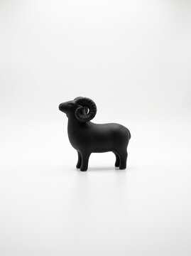 白背景に配置した黒い羊のフィギュアと干支の置物