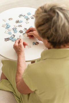 Elderly woman hands working on puzzle engage in mental and brain training to prevent dementia. Cognitive exercises for mental stimulation in older adults