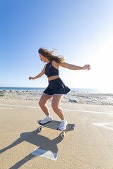 Skater practicing tricks on a skateboard along the beach boardwalk © KONSTANTIN SHISHKIN