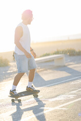 Skater rides skateboard on pathway during sunset in a coastal area © KONSTANTIN SHISHKIN