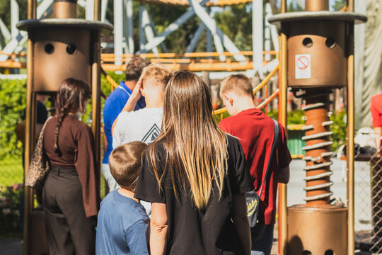 A queue for an amusement park ride.  A young woman and her son waiting their turn.