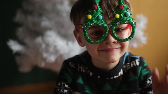 Christmas holiday. Portrait of joyful child wearing funny Christmas eyeglasses at home