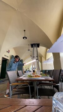 photographer leans forward behind communal table aiming camera and long led tube light at plated salads and condiments, creating directional highlights on dishes