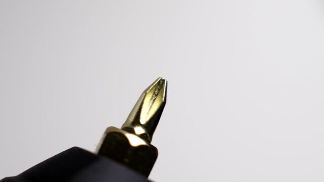 Golden crosshead screwdriver bit spinning during a test launch. Electric tool attachment close up