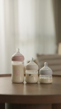 Set of Three Different Sized Baby Milk Bottles on a Wooden Table