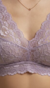 Close-up of a woman wearing a delicate lavender lace bralette and a gold necklace