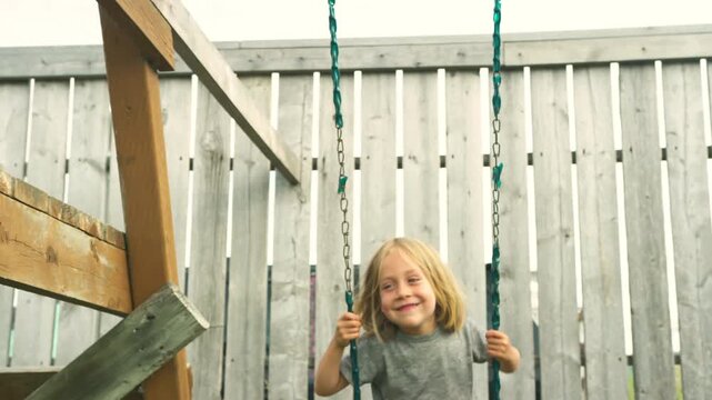 Close-up of a boy smiling while swinging in warm golden light