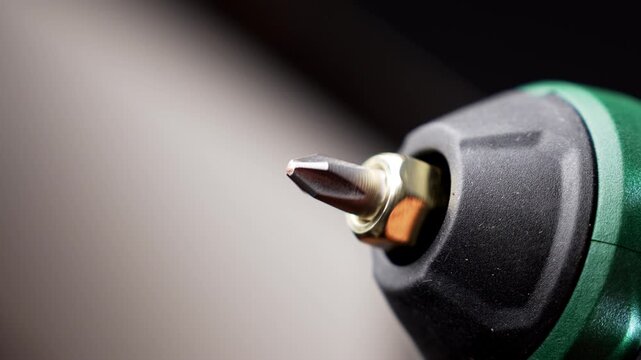 Cordless power screwdriver with a rotating chuck and attached metal driver bit during a test activation