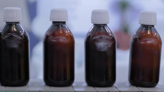 Conveyor belt with empty amber glass bottles at plastic packaging exhibition or factory: close up, side view, production line, demonstration mode of bottle shrink sleeve labeling machine
