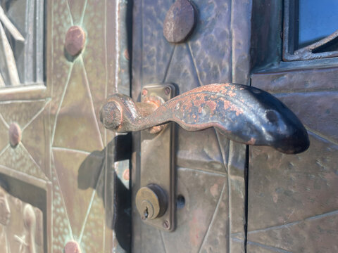 Close-up of decorative metal door handle and handcrafted metal door