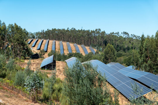 Vista panor&acirc;mica de m&oacute;dulos solares em grande escala integrados na paisagem em meio a um parque fotovoltaico sob as colinas verdejantes
