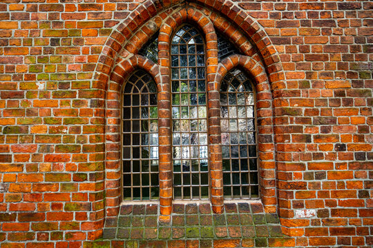 Window with decorative brick arches. Window in old church exterior. Gothic lancet window within historic architecture. Vintage glass window on medieval facade.