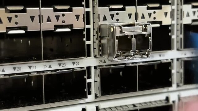 Technician hand disconnecting a blue LC fiber optic patch cable from an SFP module on a data center network switch, close up