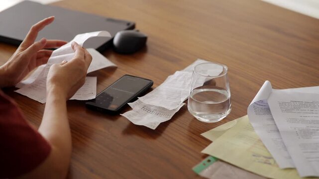 Woman Holding Paper Receipts And Using Smartphone Calculator And Checking Payment Invoices. Budget Management 