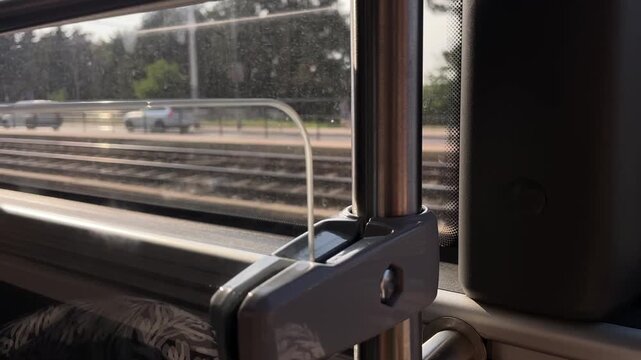 close-up view of train interior focusing on vertical stainless rail, plastic latch, and small pull-up glass panel transitioning from raised to lowered position latch