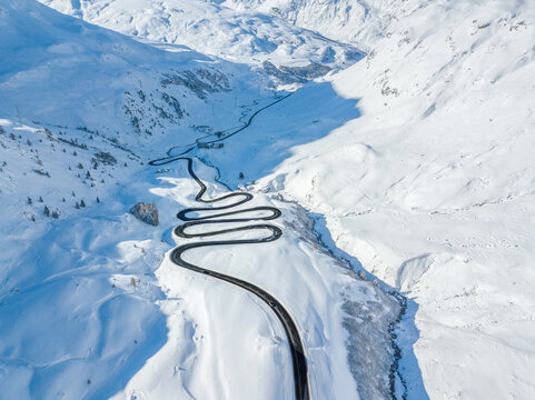 Drone view of the winding road over the  Julier Pass in Swiss Alps mountain in winter Canton Grison, Switzerland. Julier Pass is the only pass that is open through the year in Switzerland.
