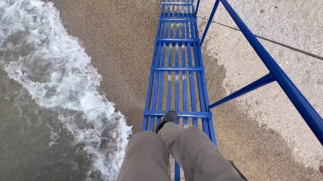 Close up of cameraman legs stepping down from boat ladder to shore