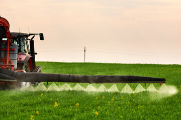 Tractor spraying agricultural field with pesticide, protecting green wheat crop © oticki