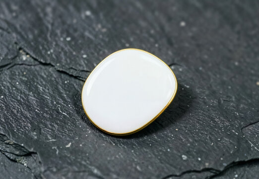 Blank oval enamel pin on dark stone background, ai generated. Minimal badge with thin gold metal border mockup with empty space for custom logo, artwork, branding or personalized design.