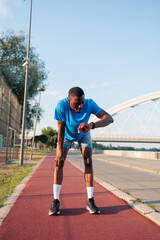 Obraz premium Male athlete recovering from a run checking smartwatch data