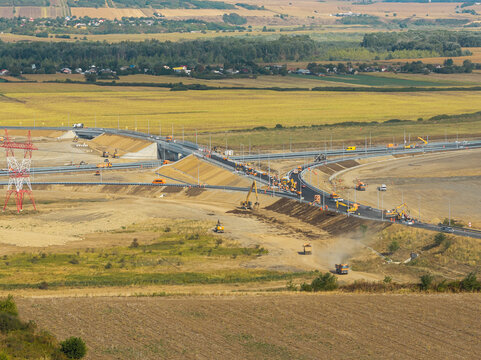 Aerial view of the Autostrada A7 junction construction near Bacau under bright daytime sunlight, showcasing modern road infrastructure, heavy machines, and rural landscape. Moldova Highway in Romania