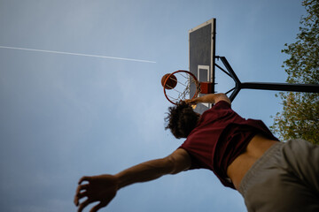 Athlete performing slam dunk on outdoor basketball court © Zoran Jesic