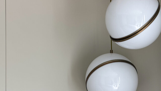 Modern spherical pendant lights with bronze details against a minimalist neutral wall in a contemporary interior.