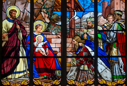 Stained glass window depicting the Three Magi offering gifts to infant Jesus, Mary and Joseph.