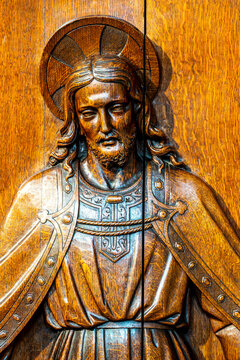 A detailed wooden relief carving depicts Jesus Christ wearing ornate robes and a circular halo.